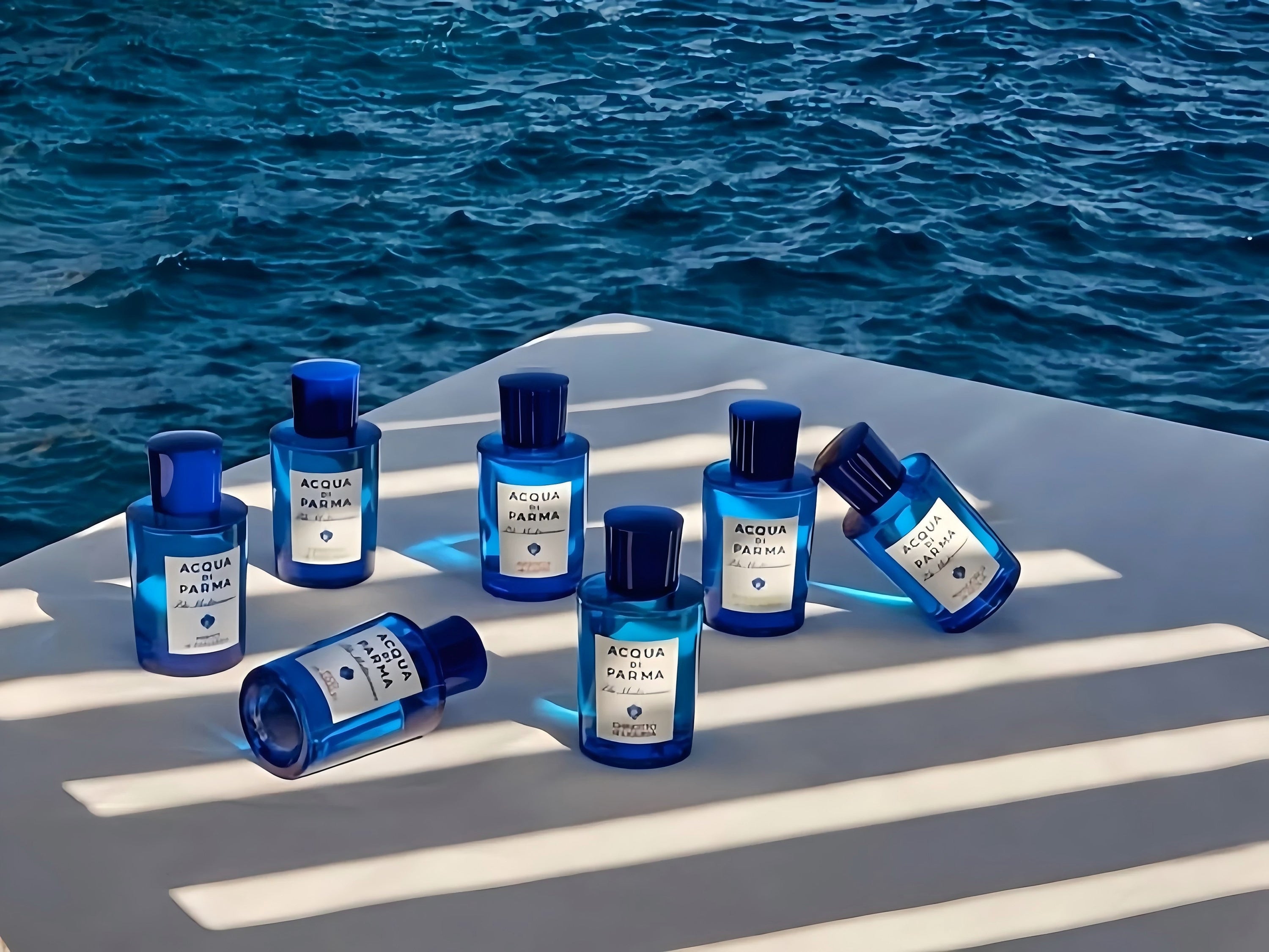 7 bottles of Acqua Di Parma displayed beside the sea, showing the Mediterranean theme.